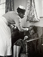 At Netherne Hospital a black nurse brushes her patient's hair, c.1955 