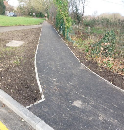 A newly laid tarmac path with grass and soil borders