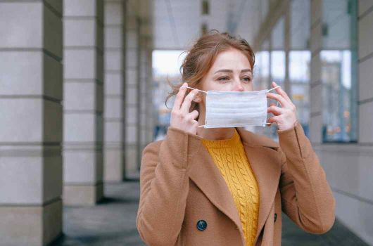 Young woman putting a mask on her face