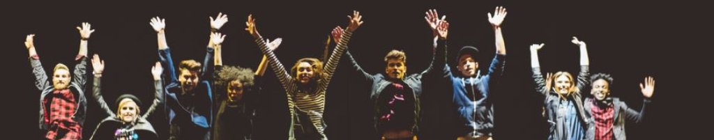 A group of people jumping in the air with their hands above their heads 