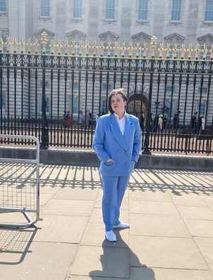 A young person standing outside Buckingham Palace.