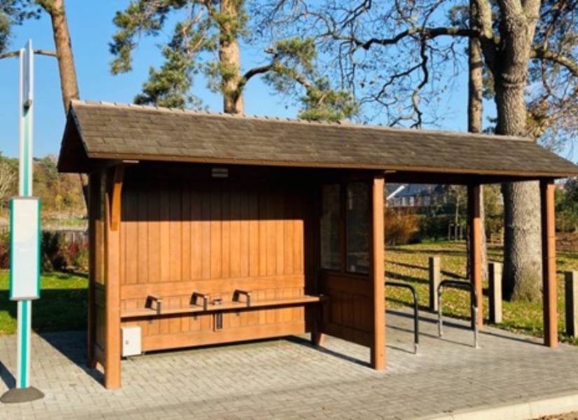 Photo of a wooden bus stop with seating area and sheltered awning