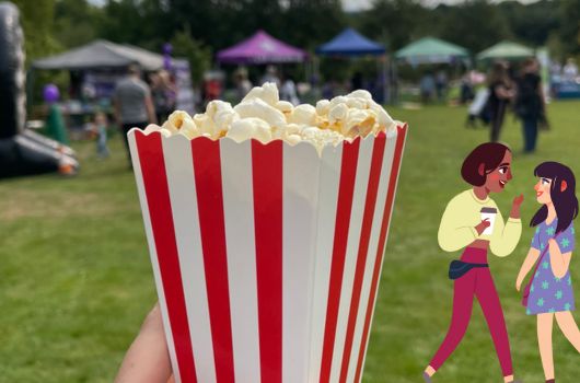 A popcorn container being held up in a field.