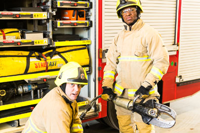 Two fire fighters holding tools used at vehicle accidents.