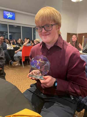 A young person sitting down holding a trophy.