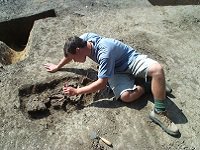 Man clearing dirt from an item at the pit site