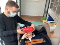 Man with mask putting a Virtual Reality headset on another man who is lying down