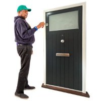 Man standing in front of a black door, holding up a key and looking
