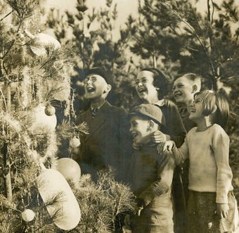 Carols round the Christmas Tree'. Photograph of children at Goldsworth Nurseries, Woking, c.1930. (Photograph by Fox Photos of London). Surrey History Centre reference: 7562/7/2 (1).