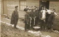 Woldingham camp - view of soldiers outside a meat store with a bucket of sausages and pig carcasses, c.1915 (SHC ref PC/161/12)